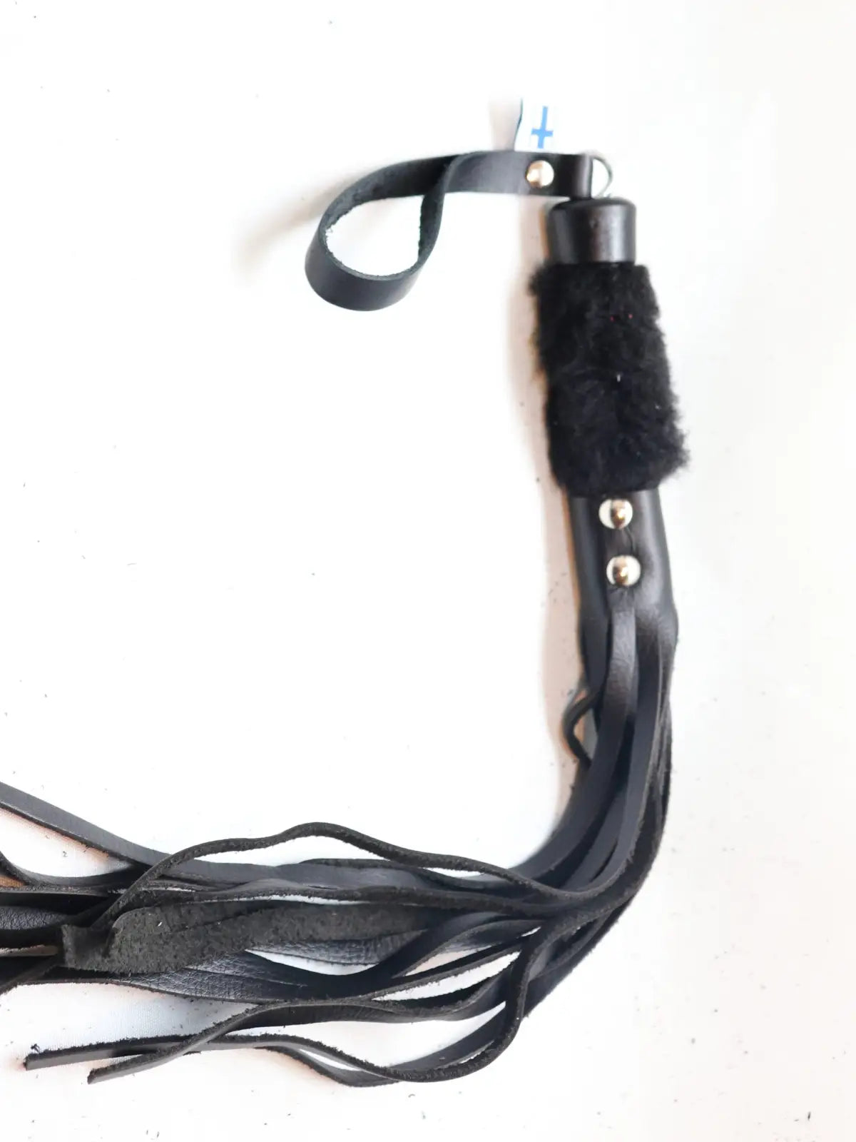 Lyhyt ruoska, jossa mustat nahkahapsut ja musta karvakahva – eroottinen ja näyttävä väline roolileikkeihin tai BDSM-käyttöön